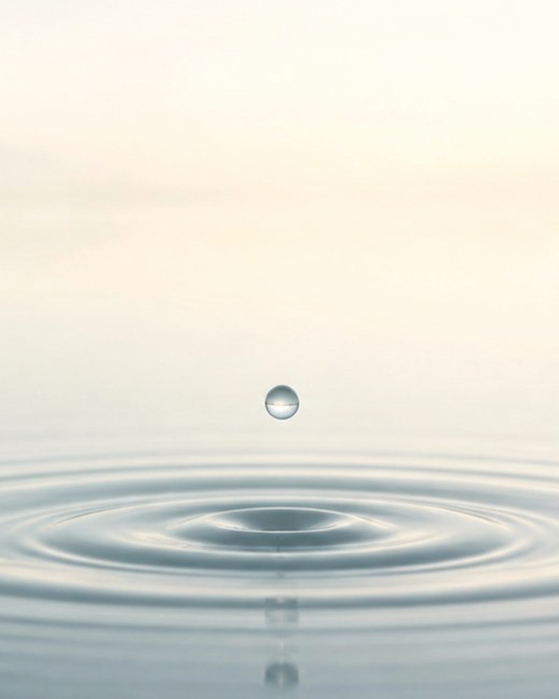 静かな水面に一滴の水が落ち、波紋が広がるようす